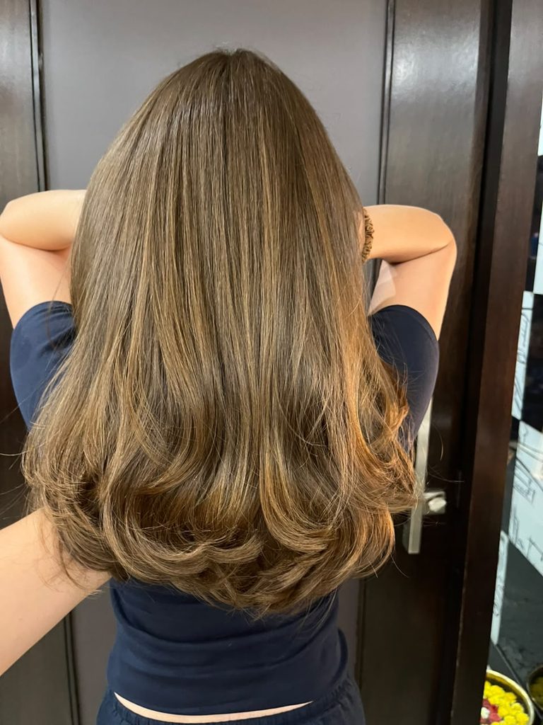 Elegant balayage hair colour featuring softly blended caramel and warm brown tones that transition naturally through the lengths, creating a dimensional, low-maintenance look
