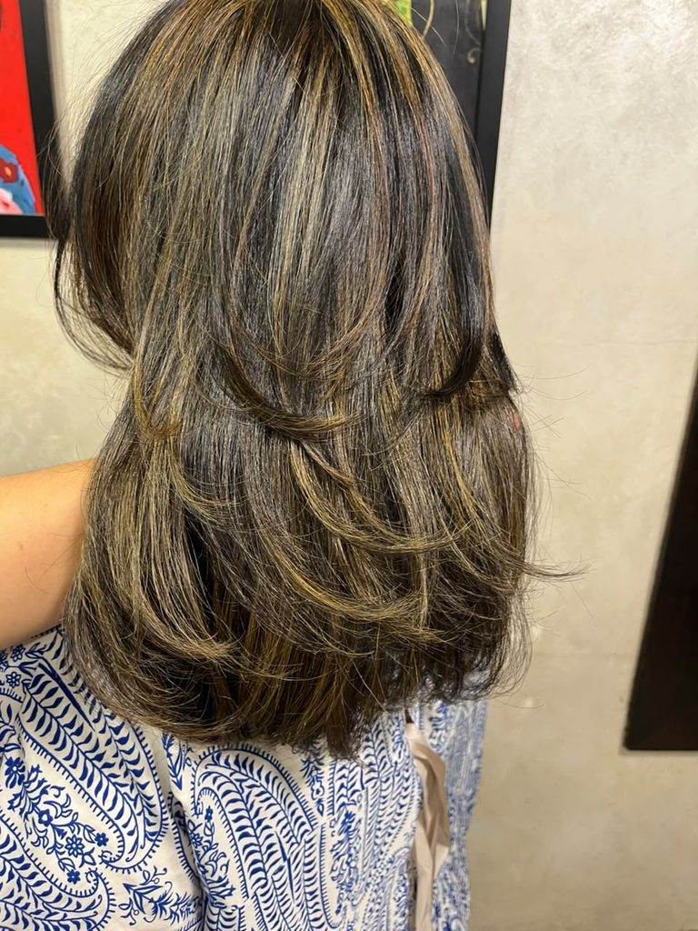 Professional hair highlights featuring defined lighter strands woven through darker hair, creating noticeable contrast, brightness, dimension and a polished multi-tonal finish